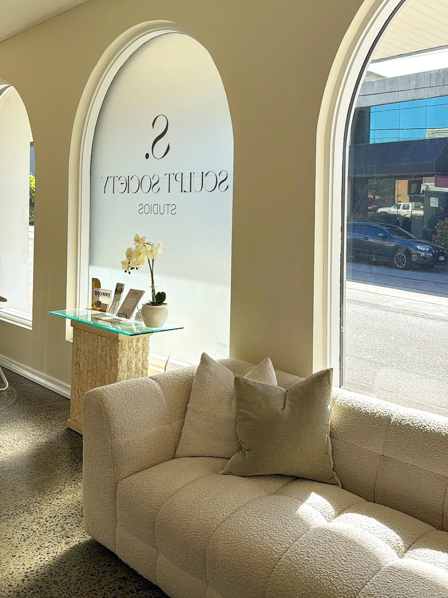 Sculpt Society reception — arched cream niche, bouclé sofa, studio signage